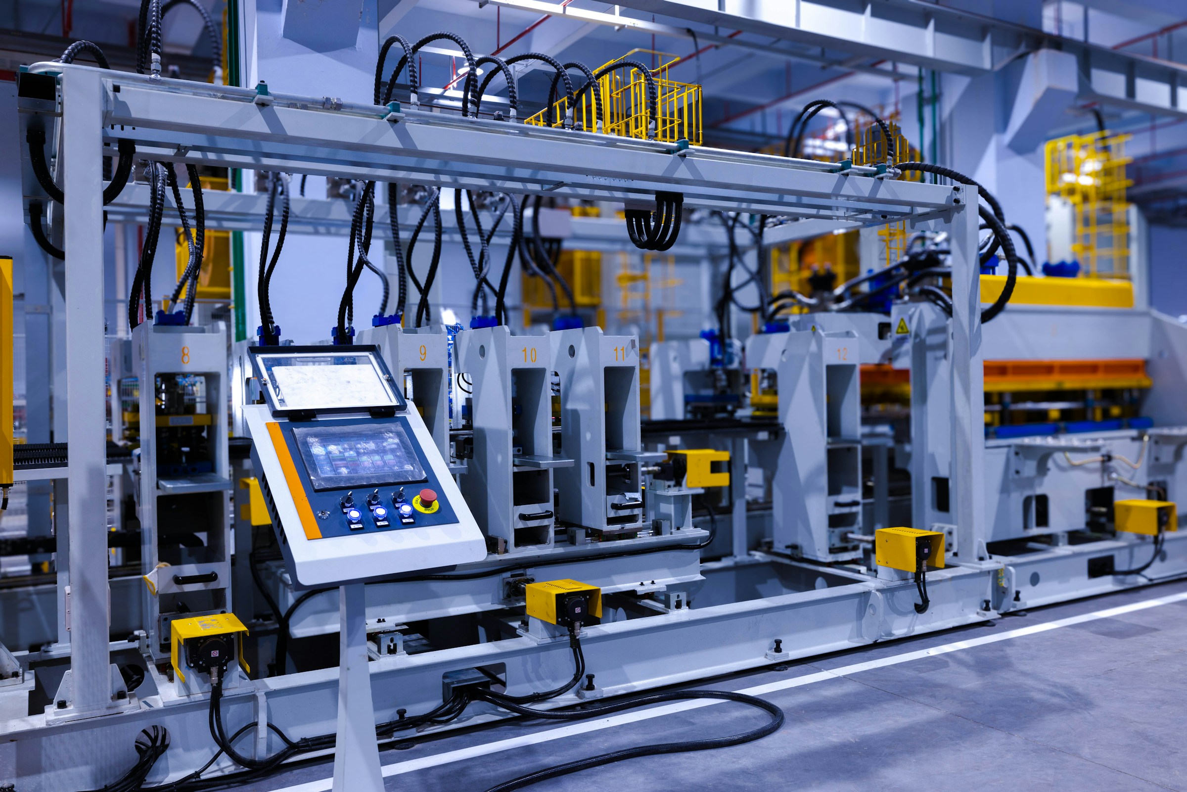 Industrial manufacturing equipment with control panel and numbered stations in a factory setting.